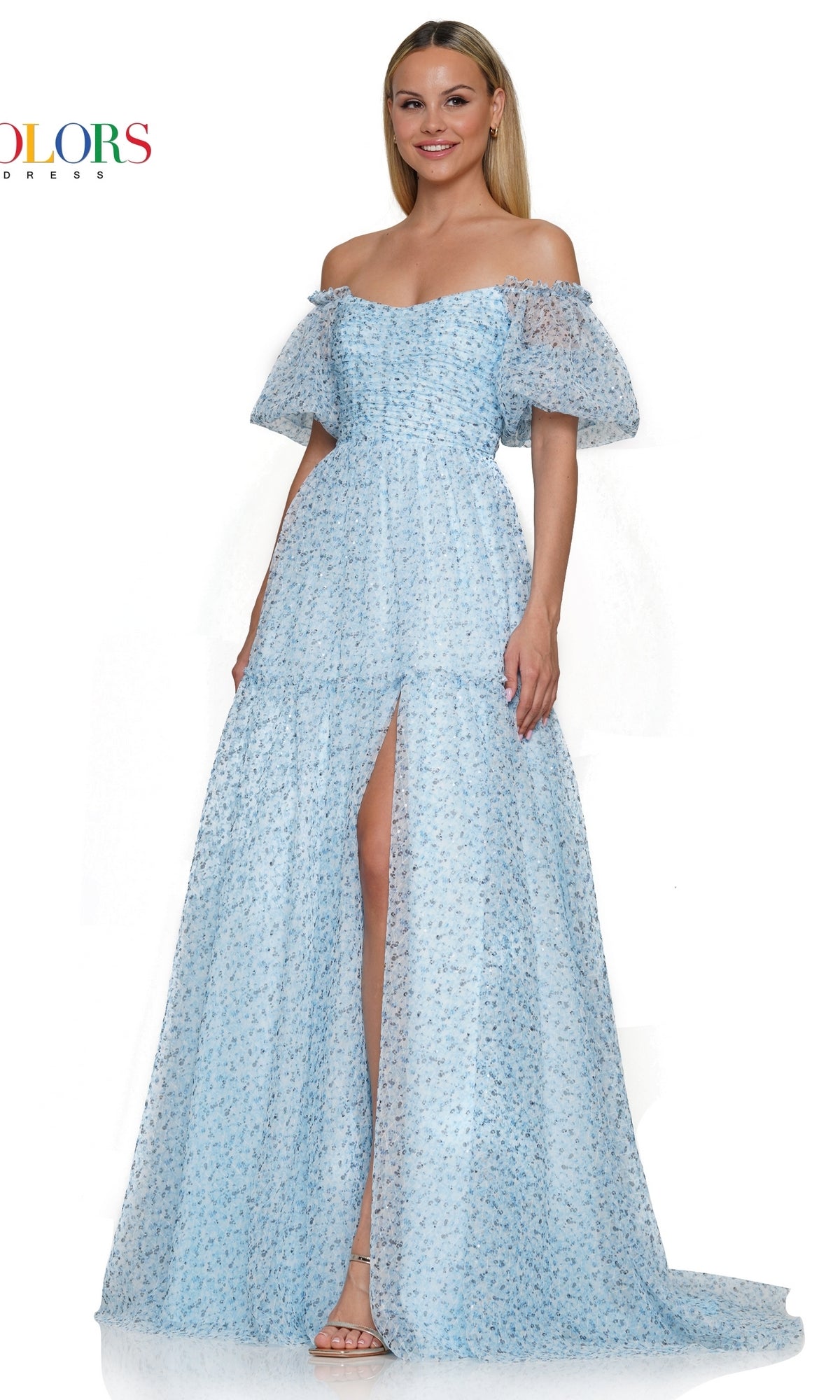 A woman wearing the Colors Dress Long A-Line Prom Dress 3190, featuring light blue fabric, puff sleeves, an off-the-shoulder neckline, fitted bodice, high slit, and a subtle floral pattern.